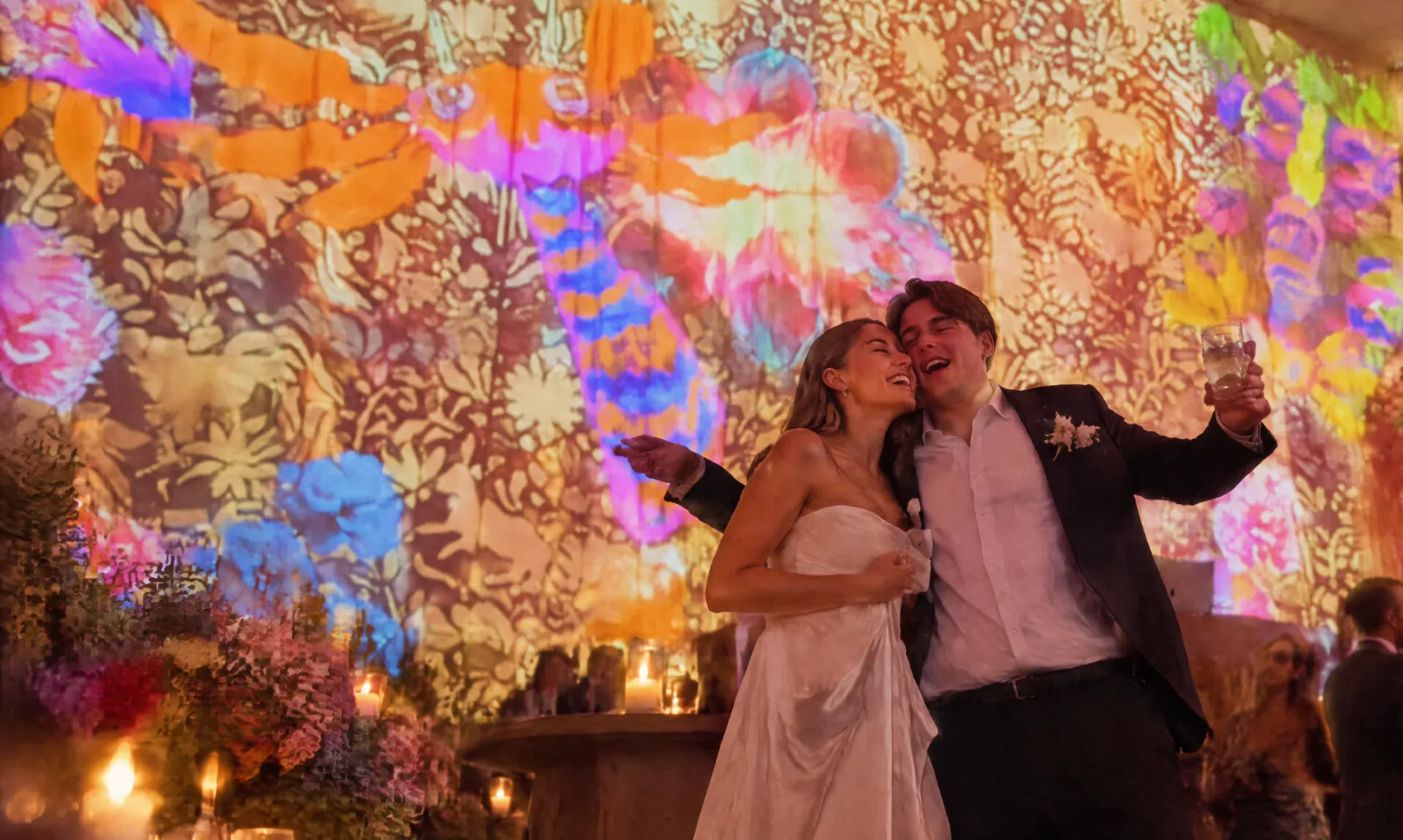 Pareja de novios celebrando frente a una fachada con videomapping floral