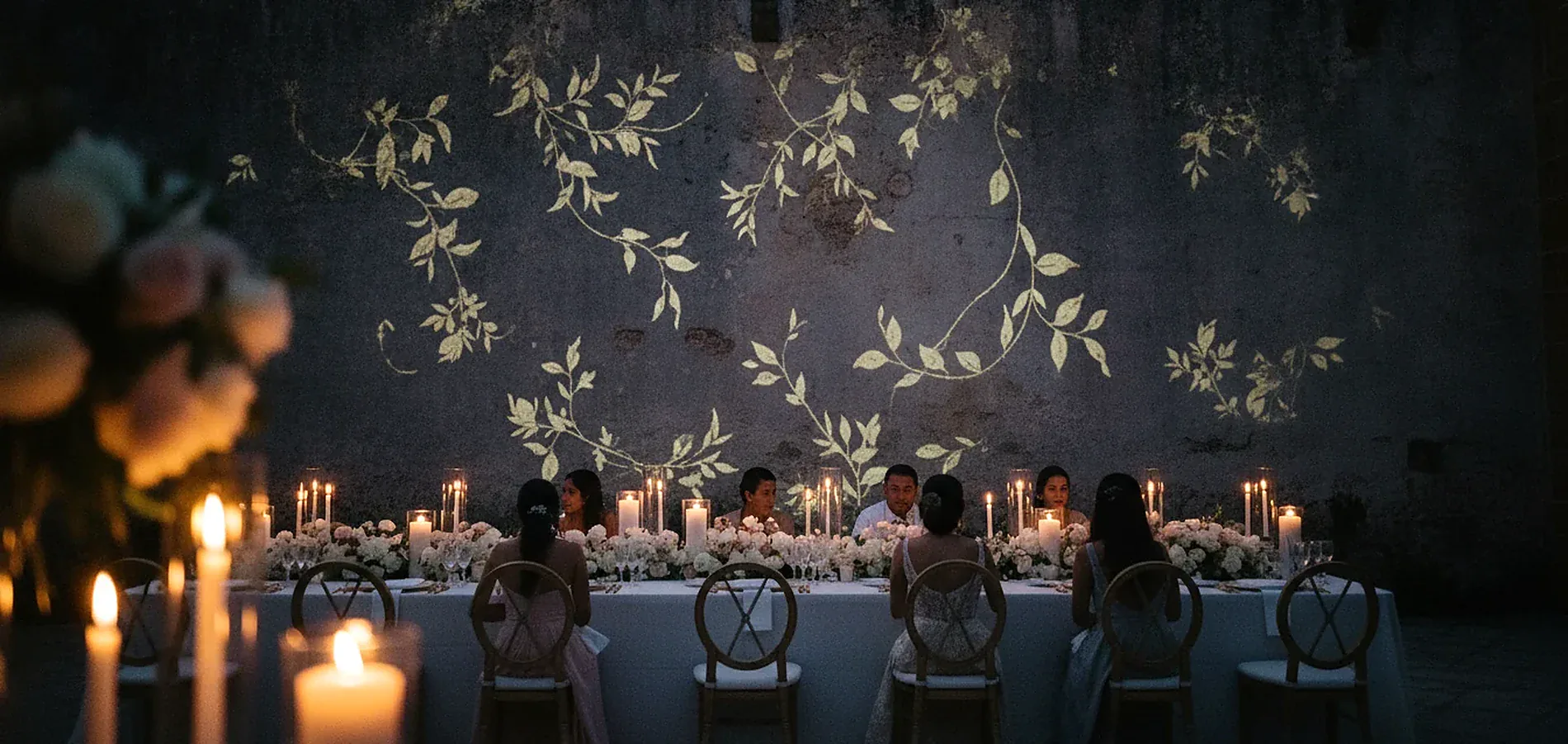 Proyección sobre el muro de una boda, con invitados frente a la luz
